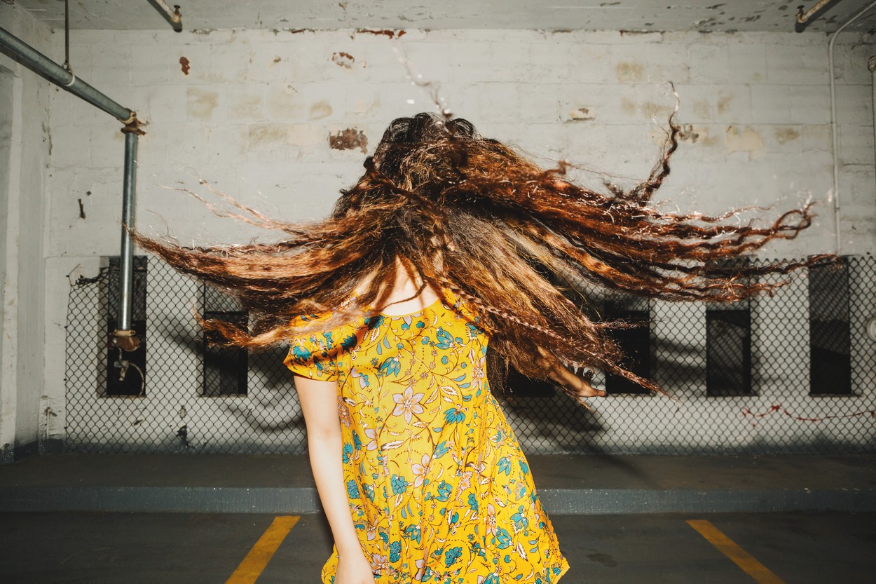 Front view of young woman shaking her long wavy hair in indoor carpark