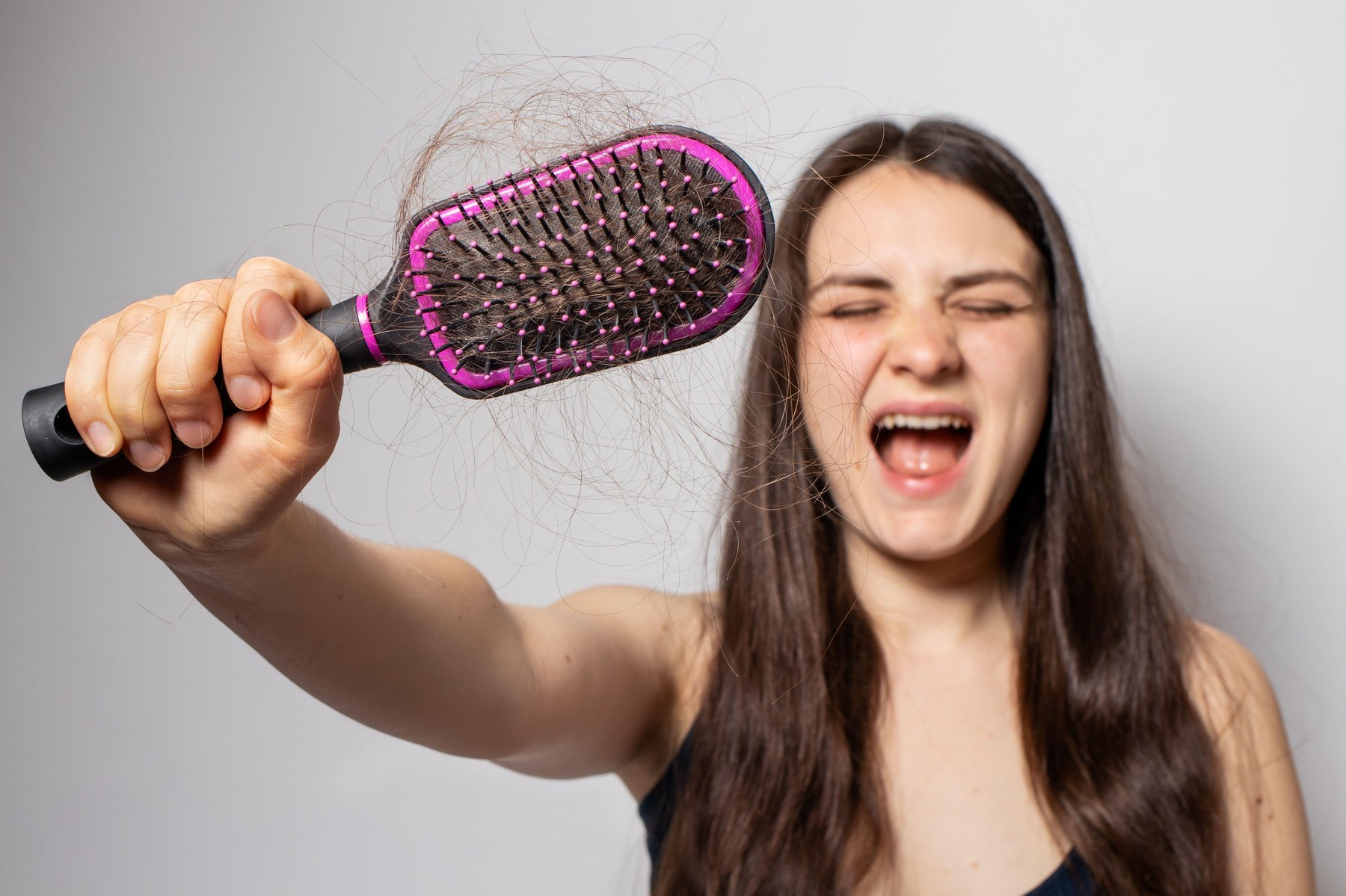 The girl holds a comb for hair with fallen hair. Hair loss, hair care.