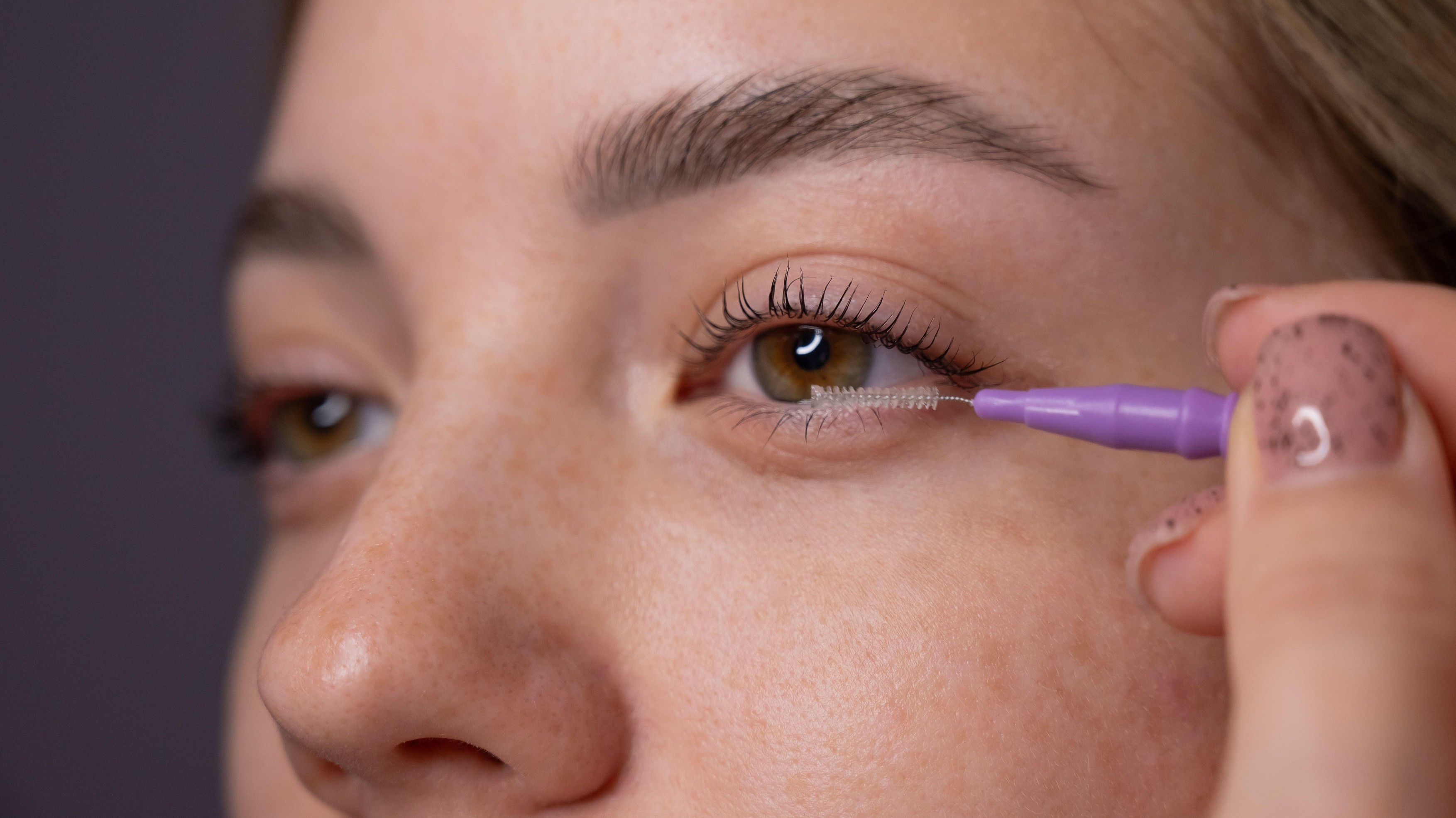 Young Woman Applying Mascara to Enhance Eyelashes.